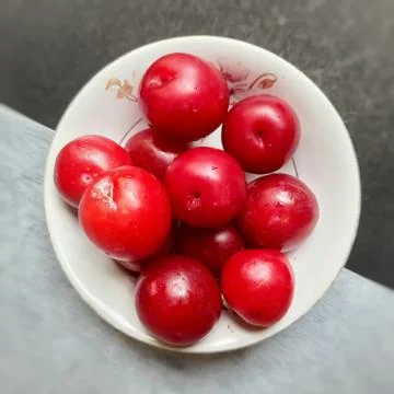 Colorful Red plums kept in bowl placed in black and white backgrounds and red Stock Photos