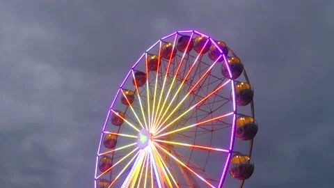 Colorful rotating nostalgic Ferris Wheel - dark cloudy sky - real time Stock Footage 140733747