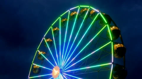 Colorful rotating nostalgic Ferris Wheel - dark cloudy sky - real time Stock Footage 140744954