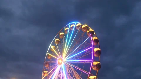 Colorful rotating nostalgic Ferris Wheel - dark cloudy sky - real time Stock Footage 140752308