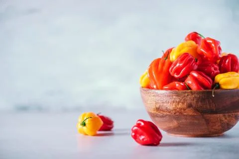 Colorful scotch bonnet chili peppers in wooden bowl over grey background. Copy Stock Photos