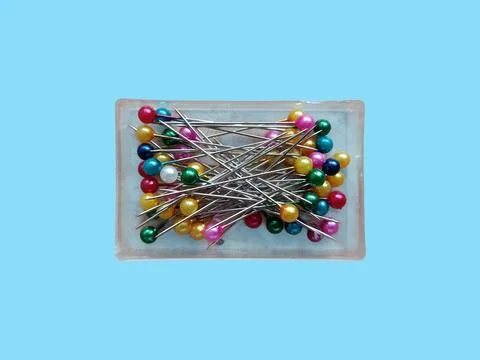 Colorful Sewing Pins in Plastic Box Isolated on Blue Background Stock Photos