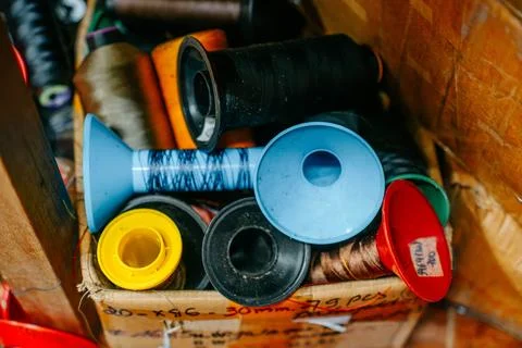 Colorful sewing thread spools and cones stored together in a busy tailoring Foto stock