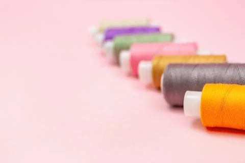 Colorful Sewing Thread Spools On Pink Background Foto stock