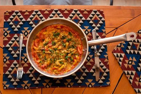 Colorful Shakshuka in a Pan on Patterned Table Mat Stock Photos