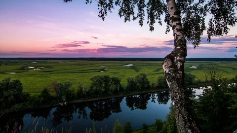 Colorful sky, clouds over the river between the forest and the field 動画素材 77267562