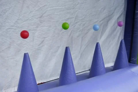 Colorful small balls hover above purple inflatable cones in a line. Fotos Stock