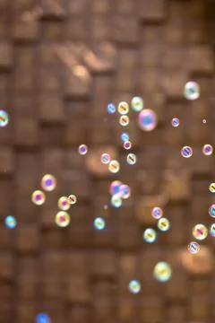 Colorful soap bubbles on blurred brown wall. Vertical iridescent background. Stock Photos