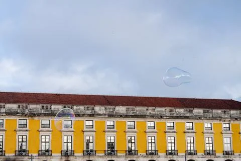 Colorful soap bubbles floating over Lisbon waterfront buildings Foto stock
