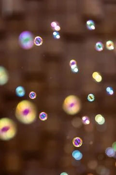 Colorful soap bubbles on warm background. Iridescent bokeh with copy space. Stock Photos