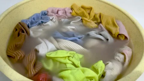 Colorful socks soaking in yellow basin with soapy water Vídeos de archivo 339722981