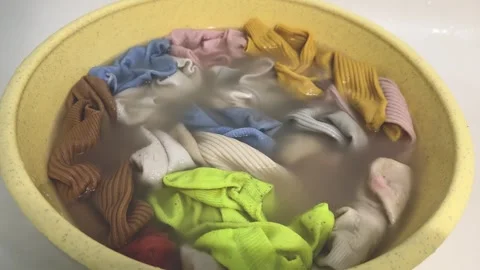 Colorful socks soaking in yellow basin with water, hand washing laundry  Vídeos de archivo 340514970