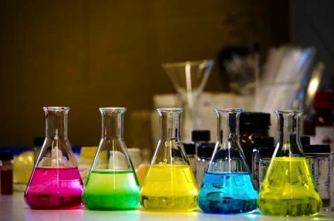 Colorful solution in conical flask lined on a bench in a chemistry lab with b Stock Photos