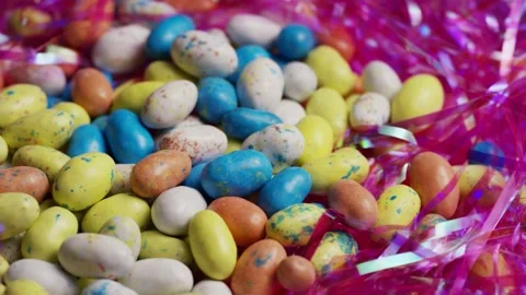 Colorful speckled easter egg candies in pink shredded tinsel Stock Footage 328136364