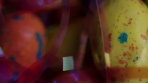 Colorful speckled Easter eggs seen through blurred pink streamers Stock Footage 327948396