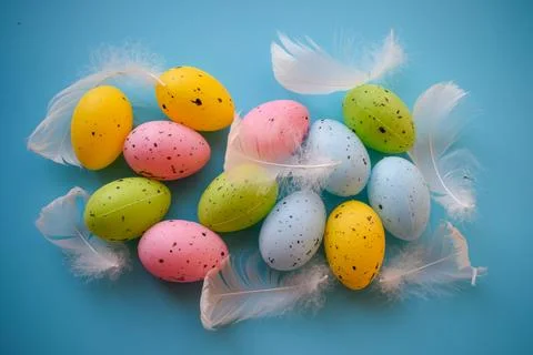 Colorful Speckled Easter Eggs with Soft White Feathers on Blue Surface Stock Photos