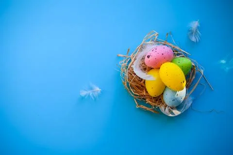 Colorful Speckled Easter Eggs with Soft White Feathers on Blue Surface Stock Photos