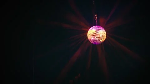 Colorful spinning disco ball creating light rays through smoke Stock Footage 346332240