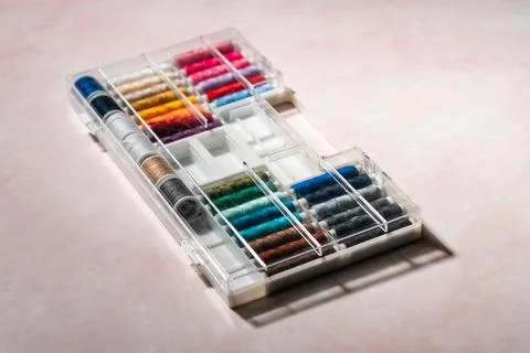 Colorful spools of sewing thread arranged in box on soft pink background. Cre Stock Photos