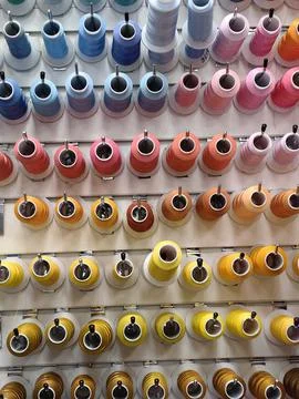 Colorful spools of thread are attached to the wall. Stock Photos