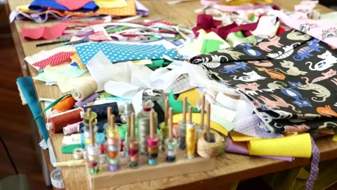 Colorful spools of thread, scraps of fabric scattered on table in game Stock Footage 274710213