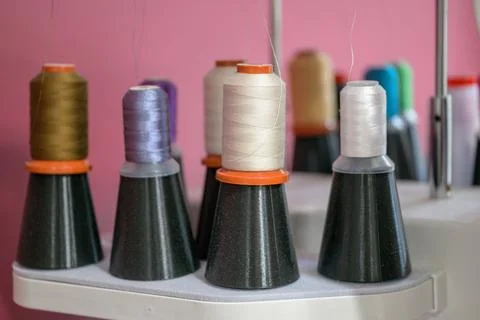 Colorful spools of thread sit neatly on a rack Stock Photos