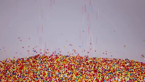Colorful sprinkles falling onto a large pile of sweet sugar beads in slow m.. Stock Footage 333775418