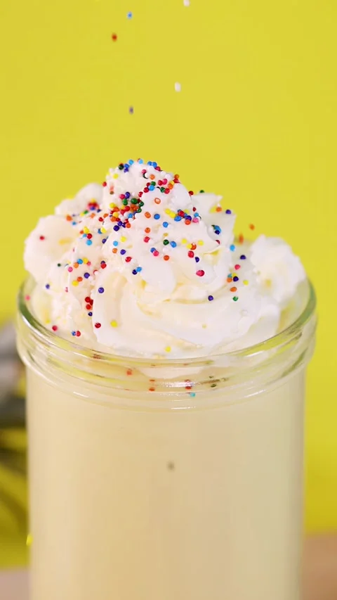 Colorful Sprinkles Falling Onto Pineapple Whipped Cream Smoothie Video stock 322581836