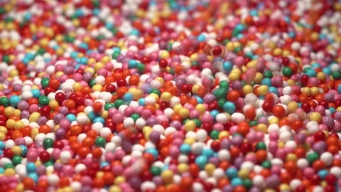 Colorful sprinkles sugar candy fall on table. multi-colored dragee fall into Stock-Footage 126257595