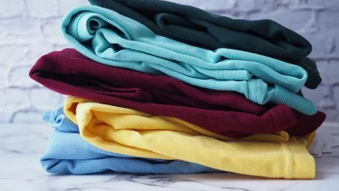 Colorful stack of clothes against brick wall, creating vibrant and organized Stock Footage 279365593