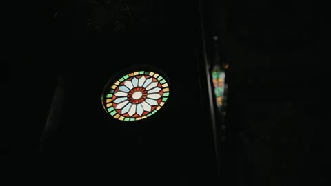 Colorful stained-glass window inside a dark church interior. The circular glass Stock Footage 320947373
