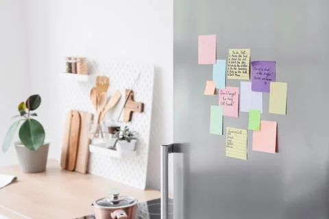 Colorful sticky notes and lists on a refrigerator door in a modern kitchen Stock Photos