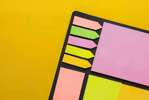 Colorful sticky notes on black notepad with yellow background Stock Photos