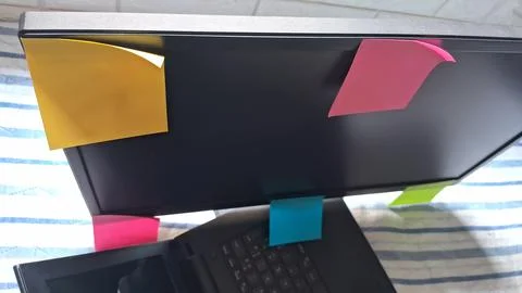 Colorful sticky notes on a computer screen. Reminders attached to a laptop for Stock Photos