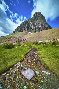 Colorful Stream and Dramatic Mountain Peak with Alpine Meadow Under Blue Sky Stock-Fotos