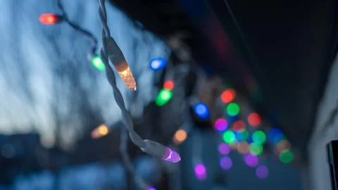 Colorful string lights are glowing in the evening twilight, creating a festive Stock Photos