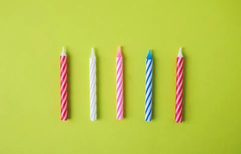 Colorful striped birthday candles on green background, top view Stock Photos