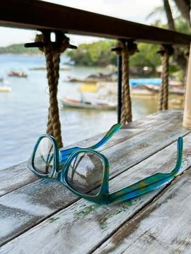 Colorful Sunglasses on Rustic Table Overlooking Tropical Bay Stock Photos