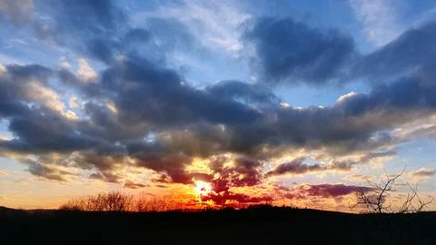 Colorful sunset background with abstract clouds and trees. Stock Photos