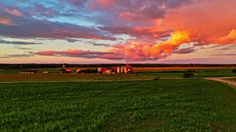 Colorful sunset clouds moving over an agricultural plant and a green cornfield Stock Footage 343733512