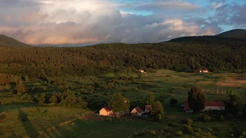Colorful sunset clouds over a pine tree forest with a rural house Stock Footage 124256891