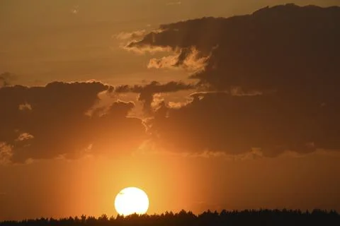 Colorful sunset in the evening. The setting disk of the sun over the forest.. 库存照片