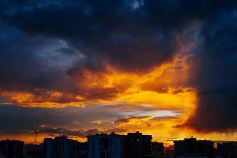 Colorful sunset forming dramatic clouds over a modern city skyline at dusk Stock Photos