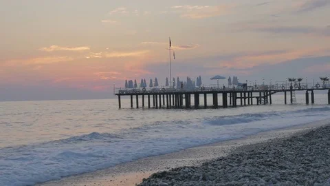 Colorful sunset on the sea. Beautiful pebbly beach with waves and pier. Stock Footage