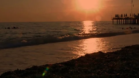 Colorful sunset. Sea view with waves and foam, pier and pebble beach Видео 80368687