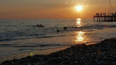 Colorful sunset. Sea view with waves and foam, pier and pebble beach Stock Footage