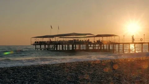 Colorful sunset. Sea view with waves and foam, pier and pebble beach Видео 82252490