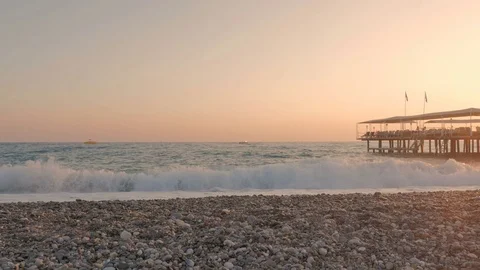 Colorful sunset. Sea view with waves and foam, pier and pebble beach Stockbeeldmateriaal 82263583