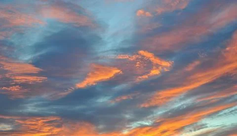 Colorful sunset sky with dramatic clouds illuminated by warm orange Stock Photos
