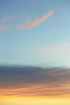 Colorful sunset sky with soft clouds and a faint moon Stock Photos
